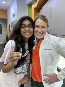 Dr. Suzanne Bird with a girl holding clear aligners
