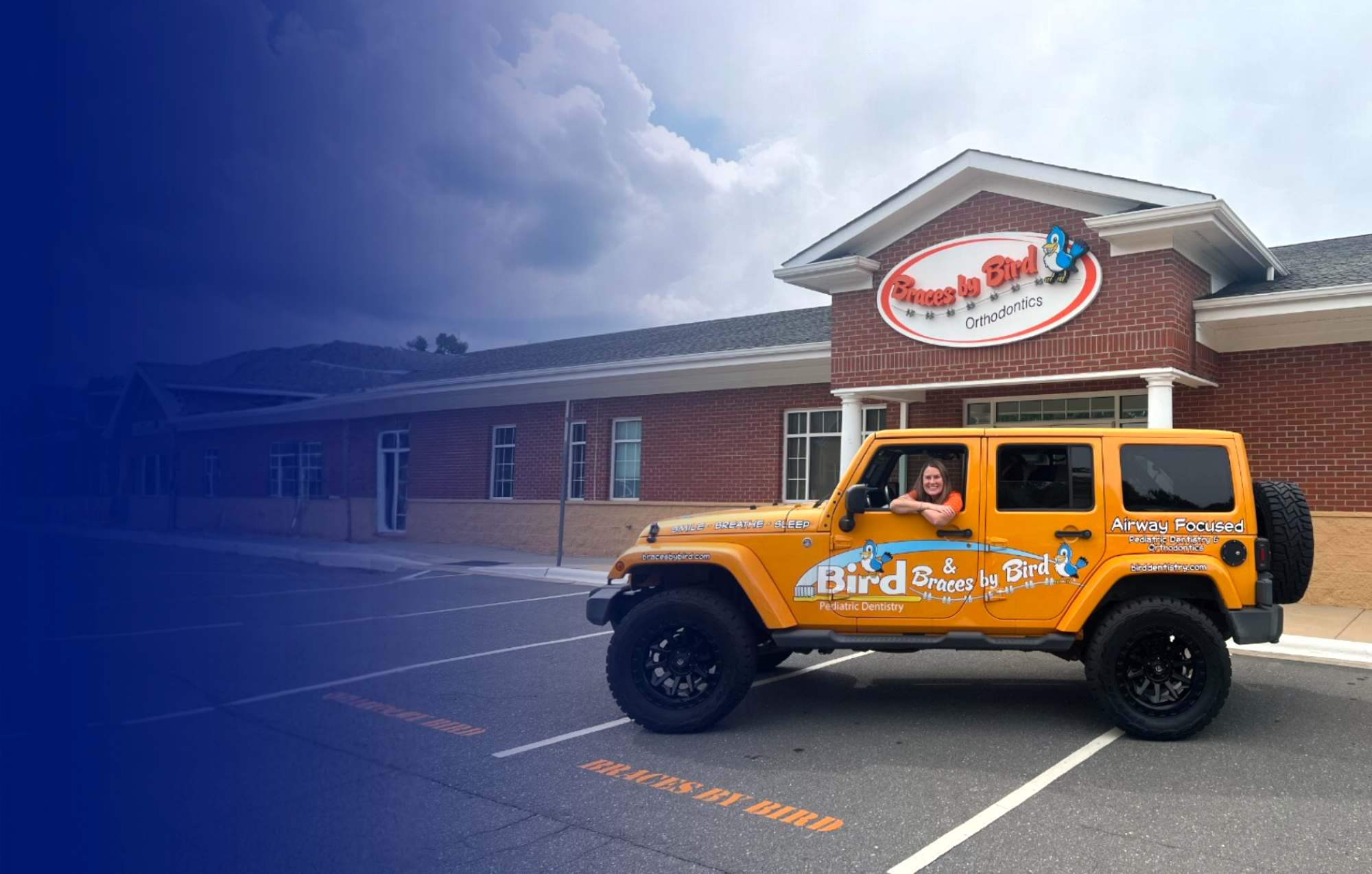 Dr. Bird sitting inside orange jeep with Braces by Bird logo in front of Dr. Bird's orthodontic practice in Charlotte